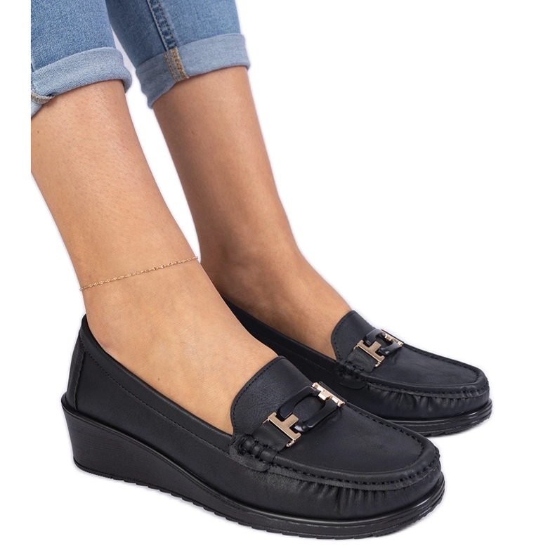 Moccasins des femmes noires sur un coin ancien le noir