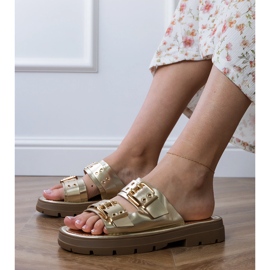 Les tongs plats dorés avec des pinces sur les rayures