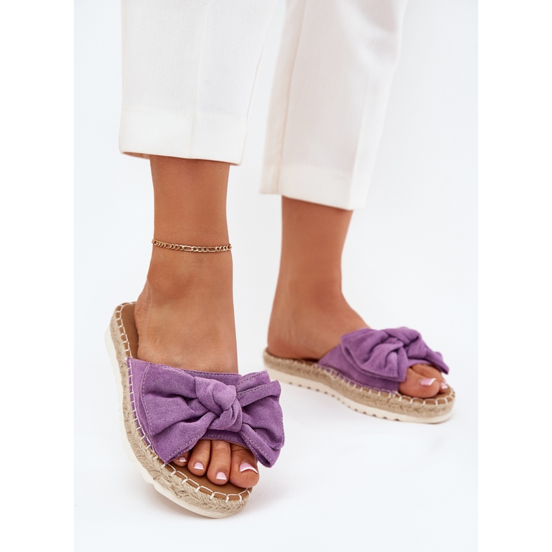 Les tongs des femmes sur la plate-forme avec une tresse et un arc violet
