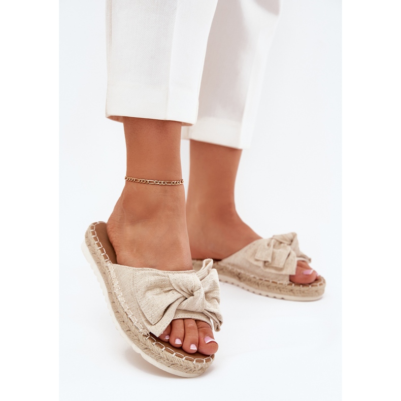 Les tongs des femmes sur la plate-forme avec une tresse et un arc beige