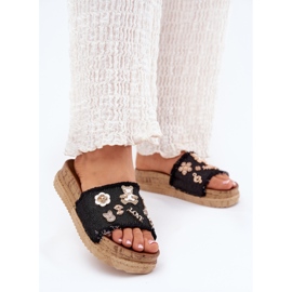 Les tongs pour femmes avec des épingles d'or sur la plate-forme noire