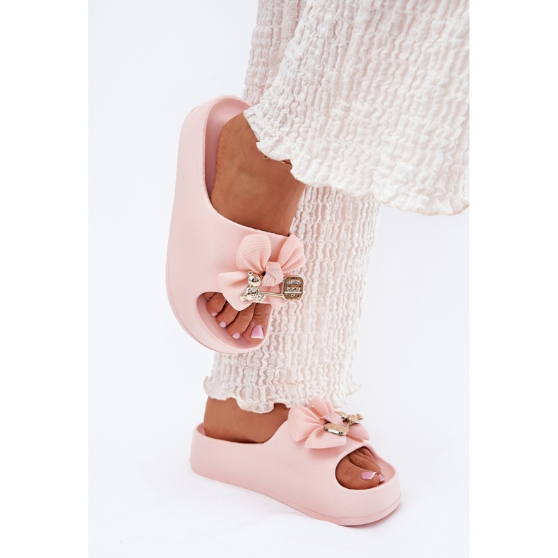 Des pantoufles de mousse pour femmes sur la plate-forme avec un arc et une broche rose