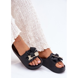 Des pantoufles de mousse pour femmes sur la plate-forme avec un arc et une broche noire