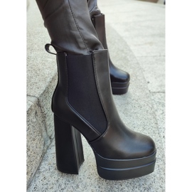 Bottes noires sur un poste élevé et une plate-forme le noir 10