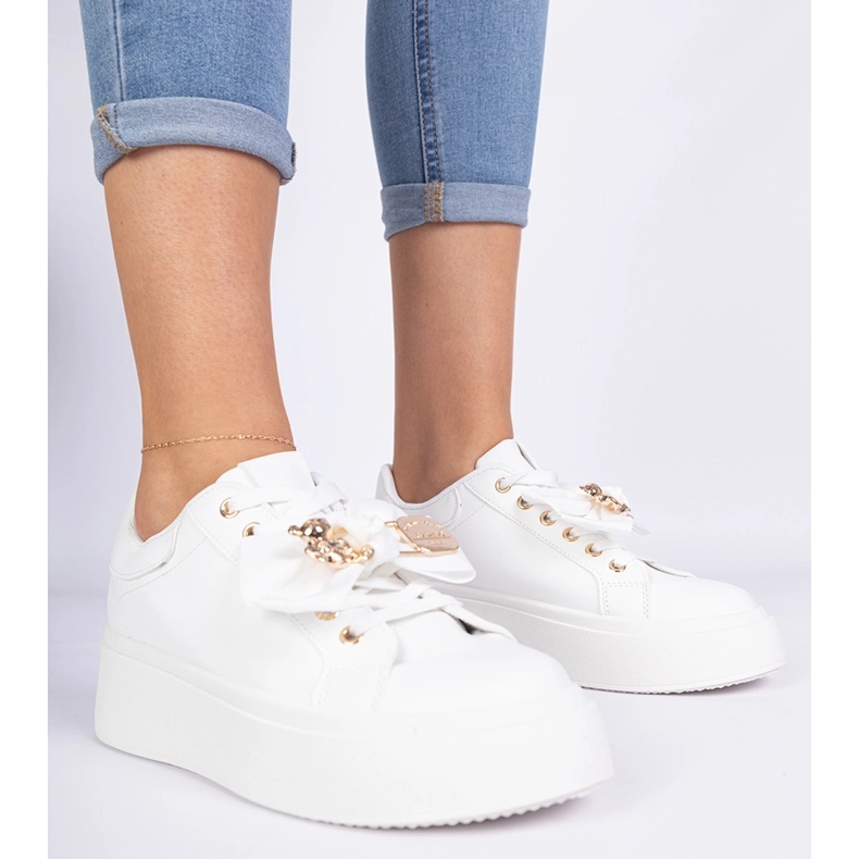 Baskets blanches décorées d'un arc et d'un ours en peluche doré 1